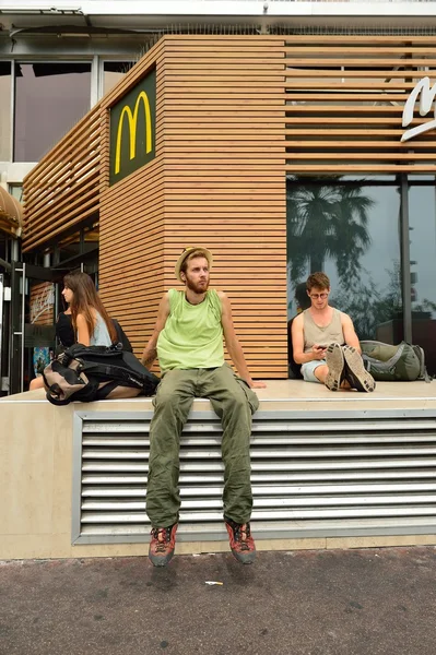 People sitting near McDonald\'s restaurant.