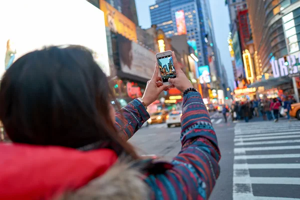 Woman taking photos in New York at evening.