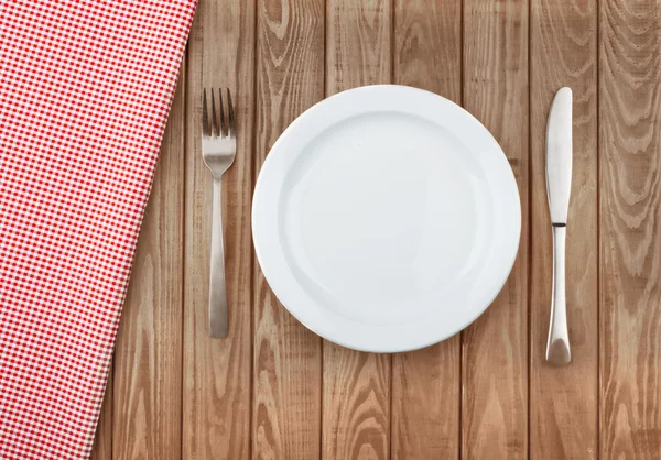 White plate and fork on old wooden table with red cloth