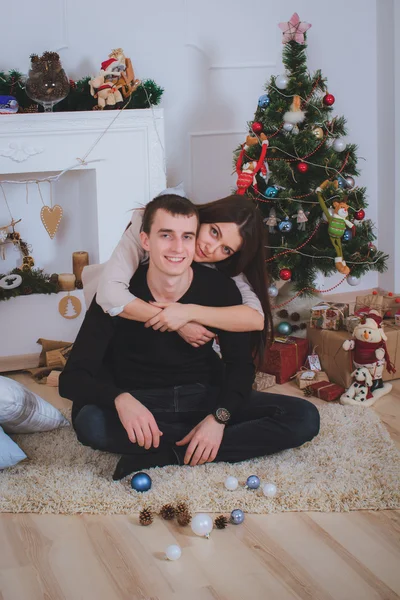Man and woman hugging, lie near the Christmas tree