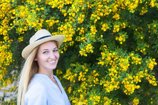 Portrait of a beautiful young woman in the hat with mimosa flowe