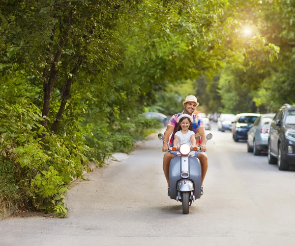 Happy young father and little daughter riding a vintage scooter