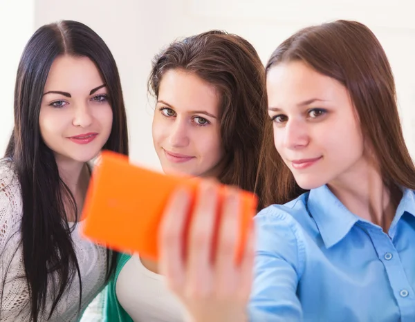 Three smiling teenage girls taking selfie with smartphone camera