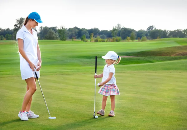 Mother and daughter practicing to hit the ball at the course