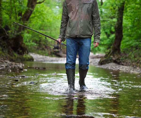 Fisherman with fly-fishing on mountain river. Spring time