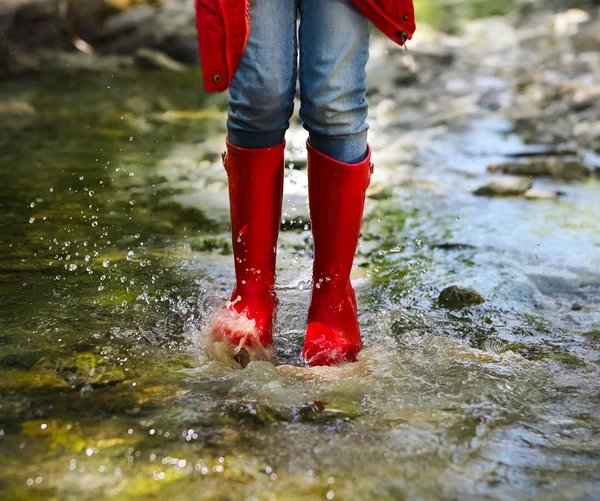Child wearing red rain boots jumping. Close up