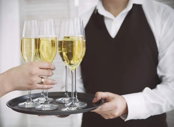 Woman taking one glass of champagne from the tray