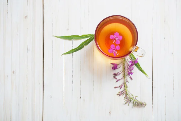 Cup of tea with willow-herb on wooden background