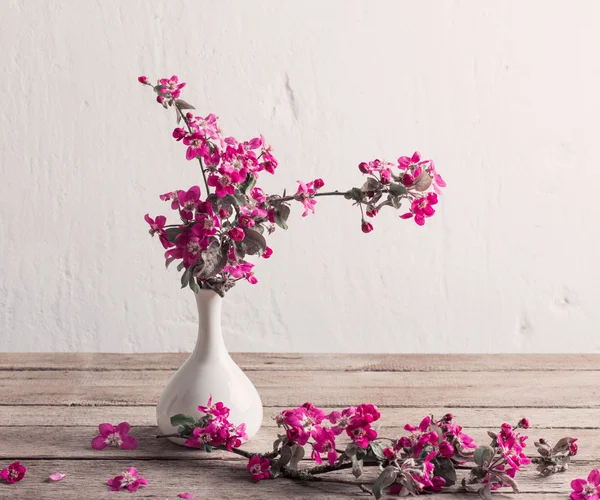 Pink flowers in vase on grunge background