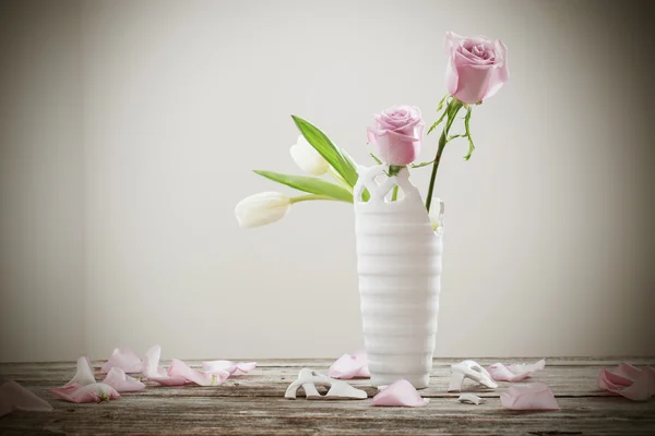 Pink roses in broken flower vase on old wooden table