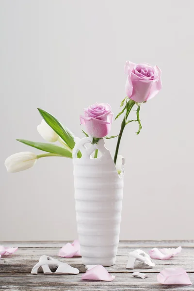 Pink roses in broken  vase on old wooden table