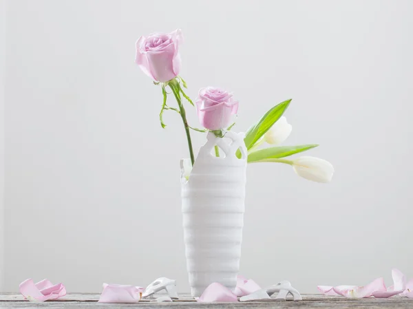 Pink roses in broken vase on old wooden table