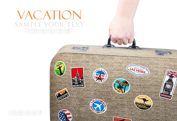 Hand holding a retro suitcase with stickers isolated