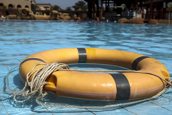 Old life buoy on the blue water of the pool.