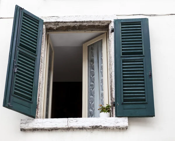 Old window with closed shutters on the window sill on the stone wall. Italian Village