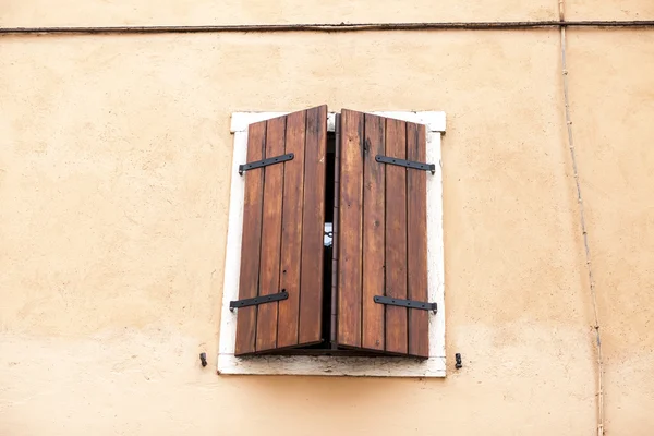 Old window with closed shutters on the window sill on the stone wall. Italian Village