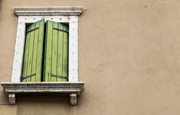 Old window with closed shutters on the window sill on the stone wall. Italian Village