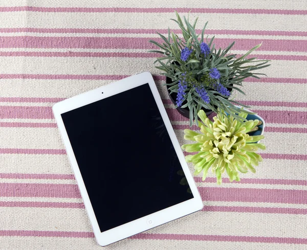 The composition of the tablet on a rustic rug with flowers