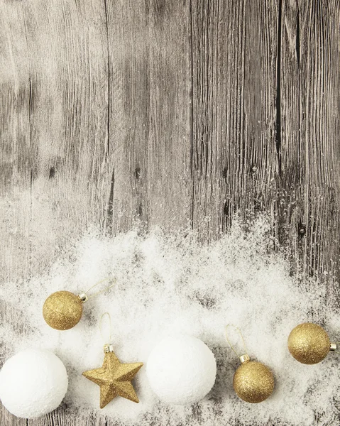 Glittering gold Christmas balls, snowballs, winter snow and star on wooden background