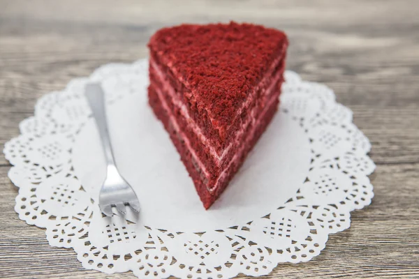 Fresh tasty sweet piece of  red velvet cake, on a white napkin and a dessert fork on a wooden background