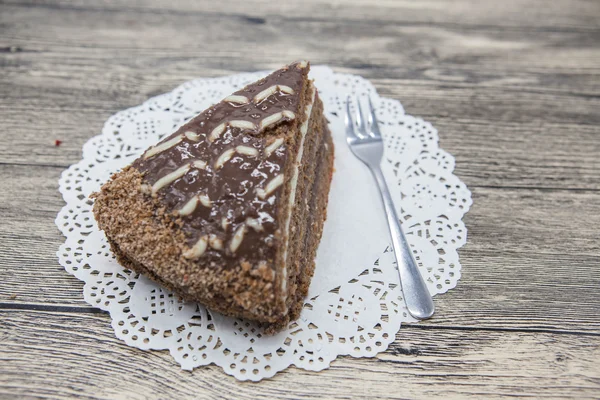 Fresh tasty sweet piece of  chocolate cake on a white napkin and a dessert fork on a wooden background