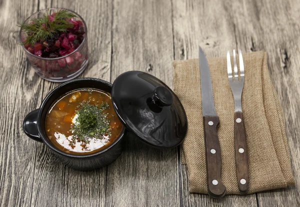 Beet  salad and tomato, red pepper soup, sauce with olive oil, rosemary and smoked paprika with fork and knife on a wooden background