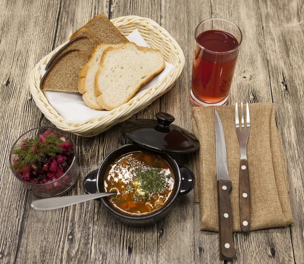 Beet  salad and tomato, red pepper soup, sauce with olive oil, rosemary and smoked paprika with fork and a glass of juice and knife on a wooden background