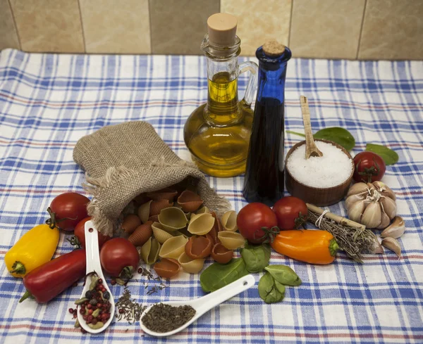 Conchiglioni Sicilian pasta set for the creation : cherry tomatoes, olive oil, balsamic sauce, garlic, spices, sea salt, salad on a rustic table