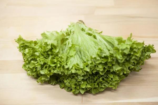Green fresh bunch of a lettuce on a wooden background . The best healthy breakfast for the modern person.