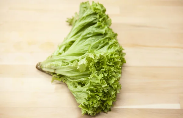 Green fresh bunch of a lettuce on a wooden background . The best healthy breakfast for the modern person.