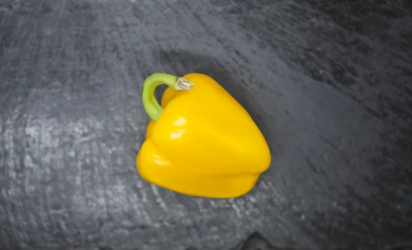 Fresh juicy yellow sweet pepper close up on a stone background.