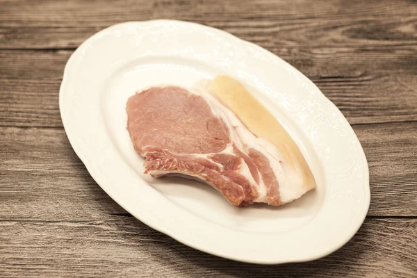 Pieces of fresh raw pork appetizing close-up on a white porcelain plate on a wooden background.