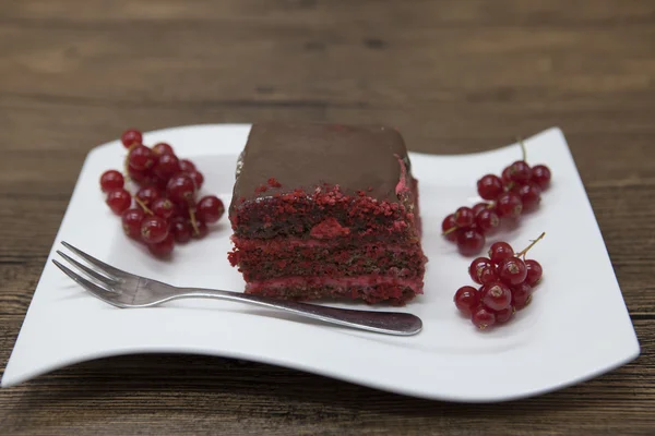 Red Velvet, fresh delicious diet cake with red currant at Dukan Diet on a porcelain plate with a spoon on a wooden background