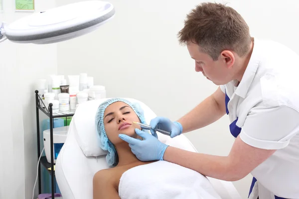 Beautiful woman gets an injection in her face.