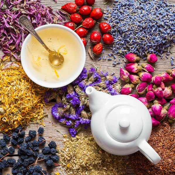 Tea kettle of healthy tea, tea cup and healing herbs