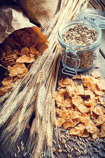 Cereal wheat flakes, spikes and rye grain on wooden table