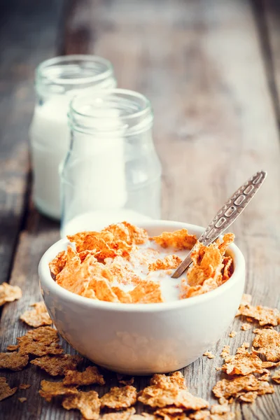 Breakfast cereal wheat flakes in ceramic bowl and milk bottles