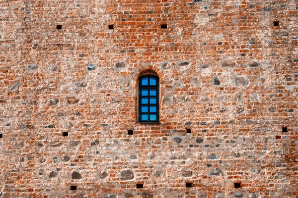 Arched window in a aged red brick castle wall