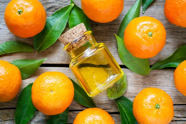 Ripe tangerines with leaves and bottle of essential citrus oil o