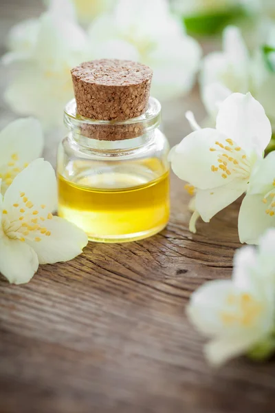 Bottle of essential jasmine oil and white jasmin flowers.