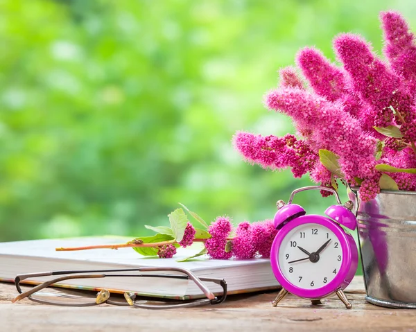Vintage still life: flowers in bucket, pink alarm clock and buck