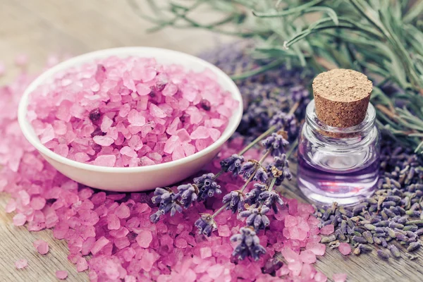 Aromatic sea salt, bottle of essential oil and lavender flowers.