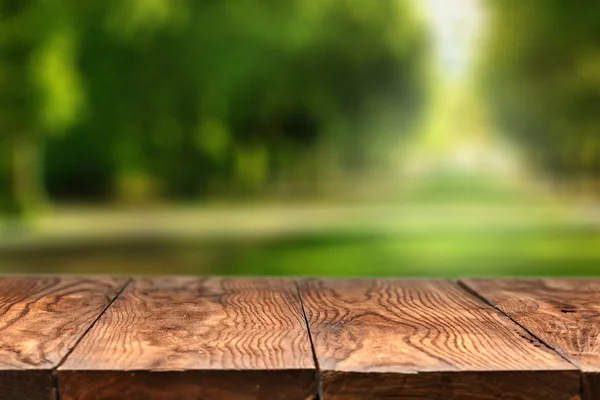 Empty wooden table with city park on background