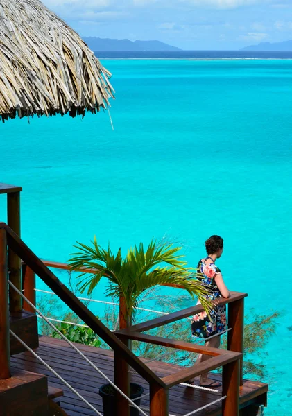 Female tourist on the balcony of an overwater bungalow