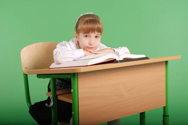 Girl in a school uniform sitting at a desk and reading a book