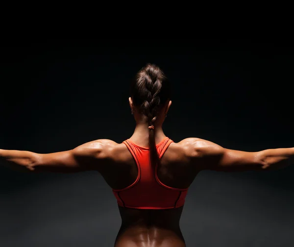 Athletic young woman showing muscles of the back