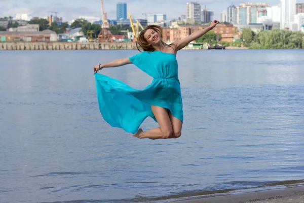 Attractive girl have fun at the urban beach in the water. Woman portrait with blue dress.