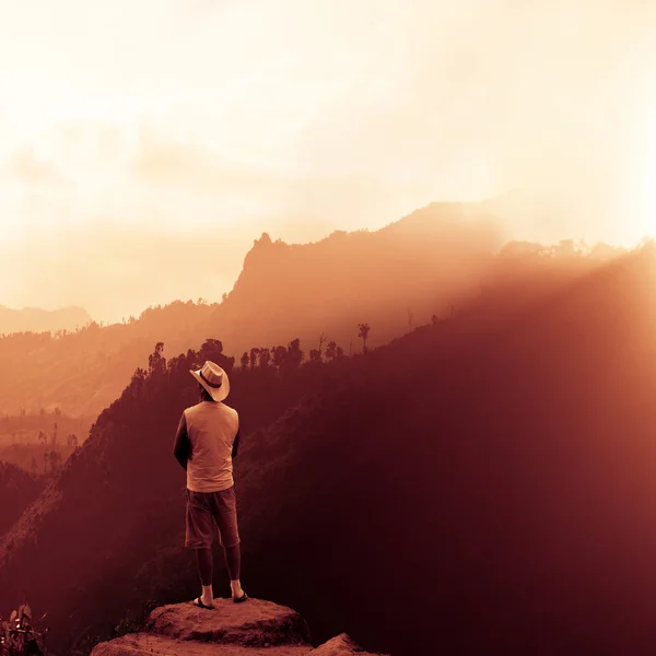 Cowboy standing on top of a mountain and enjoying sunrise