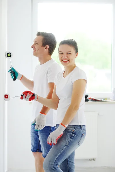 Young people paint a wall in an empty apartment