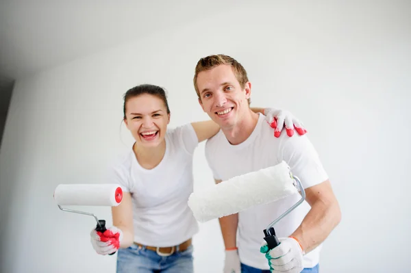 The laughing newlyweds are ready to paint walls of the house.